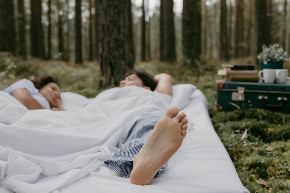 A couple peacefully resting on a white blanket in a forest setting, capturing tranquility and nature.