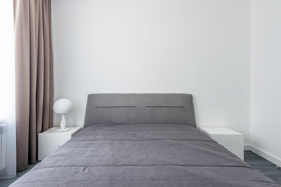A serene minimalist bedroom featuring gray bedding and modern decor elements.