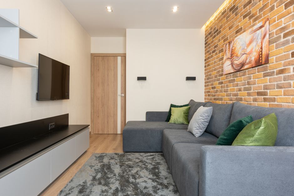 Cozy modern living room with brick wall and gray sofa, perfect for relaxation.
