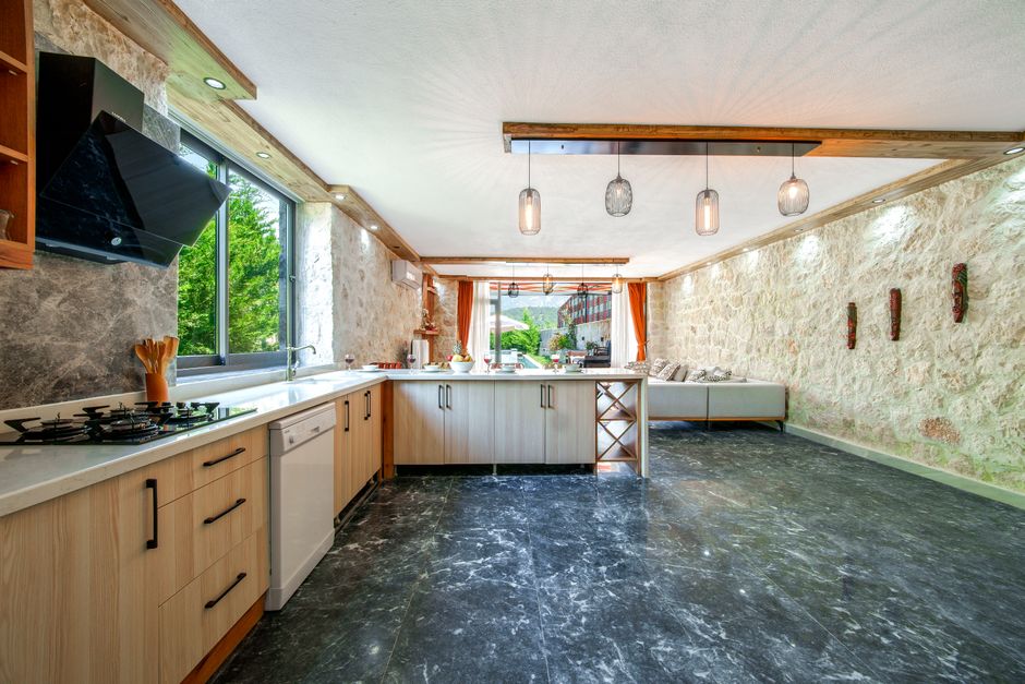 Spacious kitchen with stone walls and modern appliances, featuring natural light.