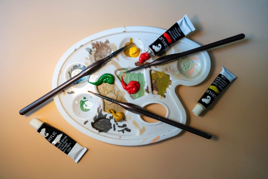 Artistic setup of a palette with acrylic paint tubes and brushes, perfect for creative inspiration.
