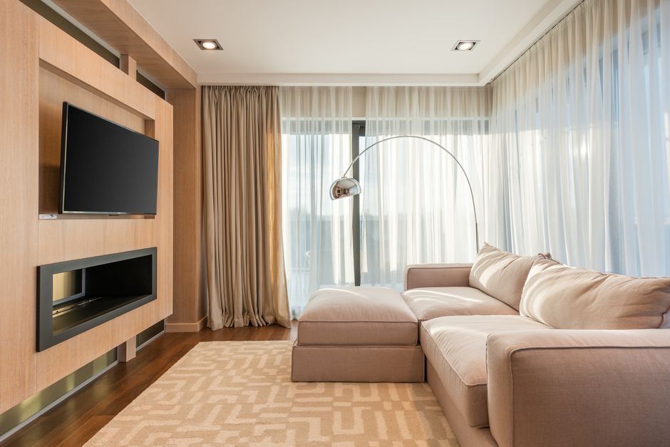 Interior of stylish living room with soft couch near window with curtains against wooden w