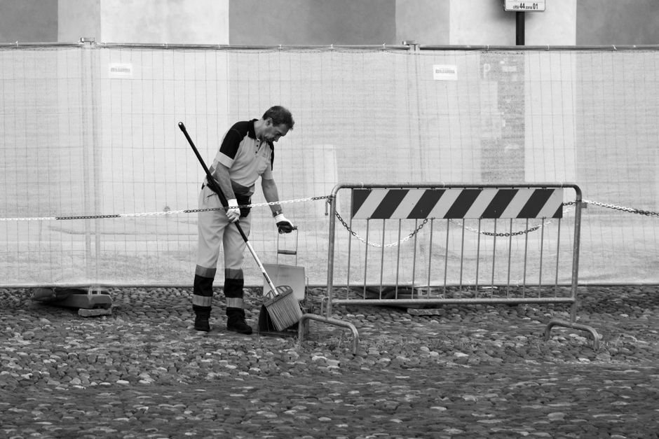 Black and white image of a street sweeper cleaning cobblestones in Mantova, Italy.