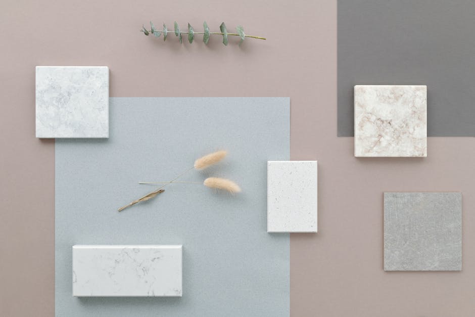 Minimalist flat lay showcasing marble tile samples with eucalyptus on a neutral background.
